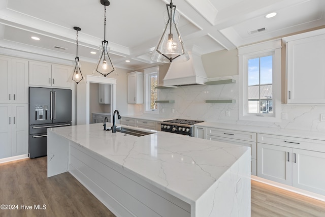 kitchen featuring premium appliances, sink, pendant lighting, a center island with sink, and white cabinetry