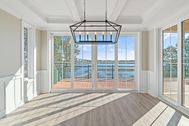 unfurnished sunroom featuring plenty of natural light, a water view, and a chandelier