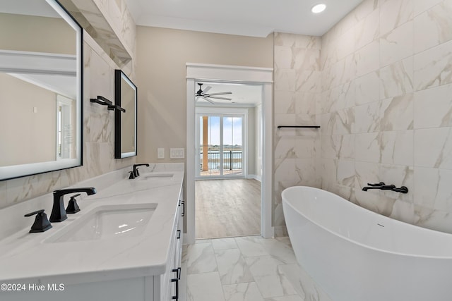 bathroom with ceiling fan, a bathtub, vanity, and tile walls