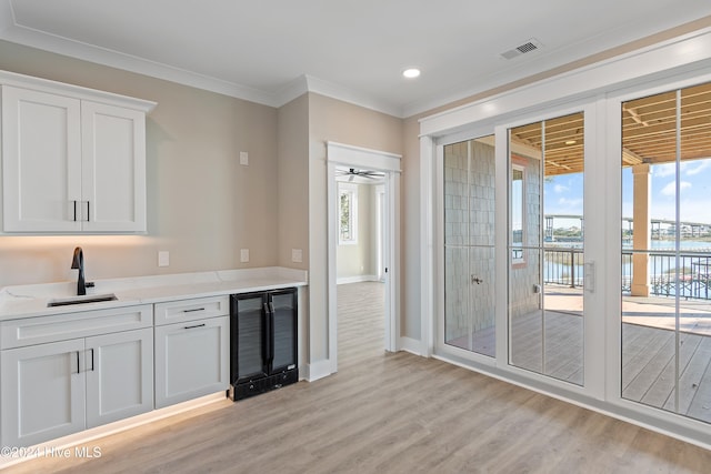 kitchen with white cabinets, light stone countertops, beverage cooler, and ceiling fan