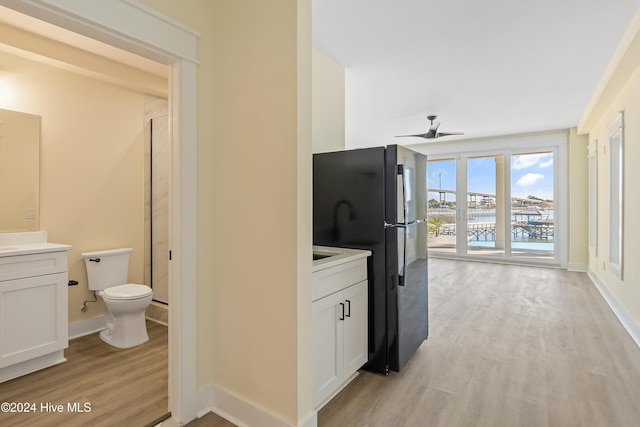 kitchen with black fridge, light hardwood / wood-style flooring, white cabinetry, and ceiling fan