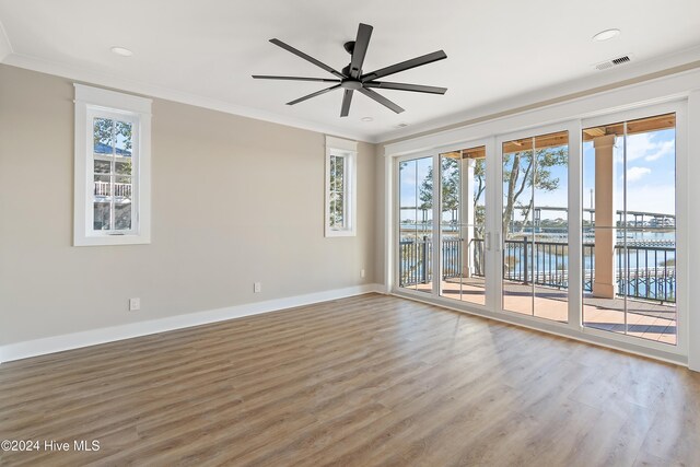 empty room with a wealth of natural light, ceiling fan, and a water view