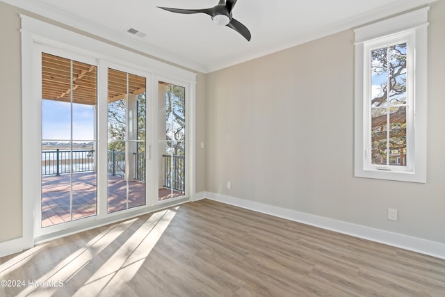 empty room with a water view, a wealth of natural light, crown molding, and ceiling fan