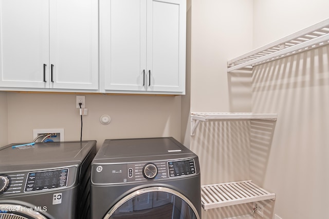 laundry room featuring washer and dryer and cabinets