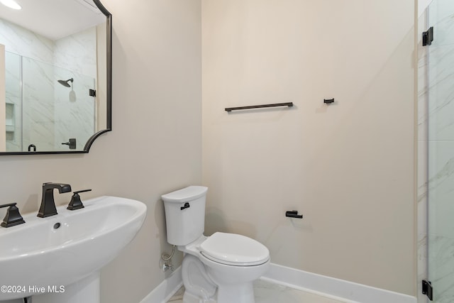 bathroom with sink, a shower with door, and toilet