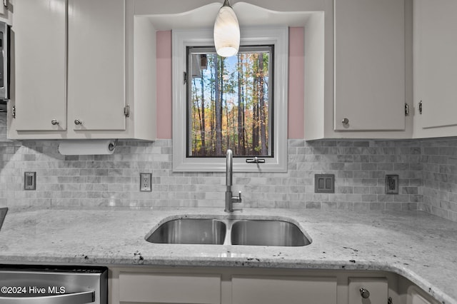 kitchen featuring white cabinets, sink, decorative backsplash, light stone countertops, and decorative light fixtures