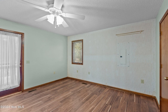 spare room with electric panel, ceiling fan, hardwood / wood-style floors, and a textured ceiling