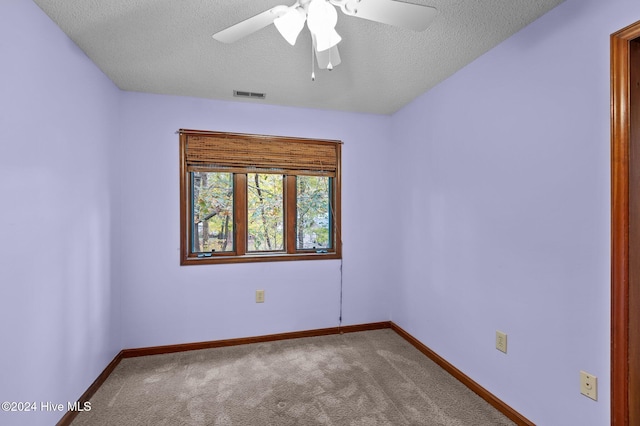 carpeted spare room featuring a textured ceiling and ceiling fan