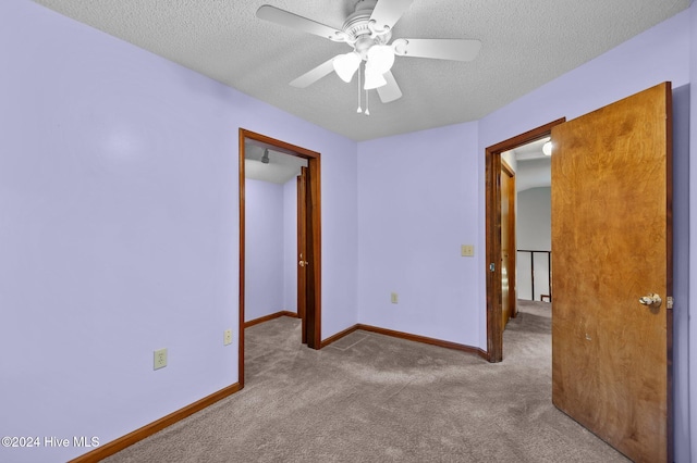 unfurnished bedroom featuring a textured ceiling, light colored carpet, and ceiling fan