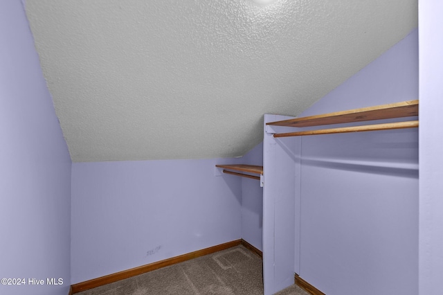 walk in closet with carpet and lofted ceiling