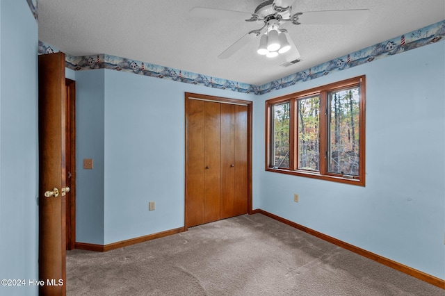 unfurnished bedroom featuring ceiling fan, a closet, light colored carpet, and a textured ceiling