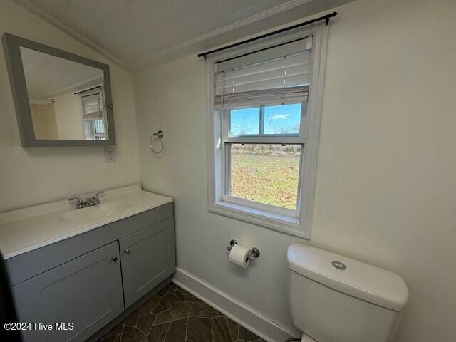 bathroom with vanity, crown molding, vaulted ceiling, tile patterned flooring, and toilet