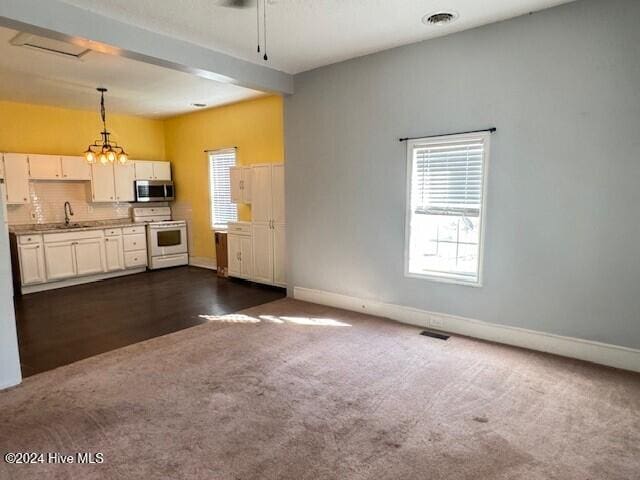 kitchen with pendant lighting, dark carpet, white cabinetry, and white stove