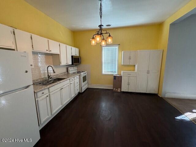 kitchen featuring white appliances, sink, white cabinets, dark hardwood / wood-style floors, and hanging light fixtures