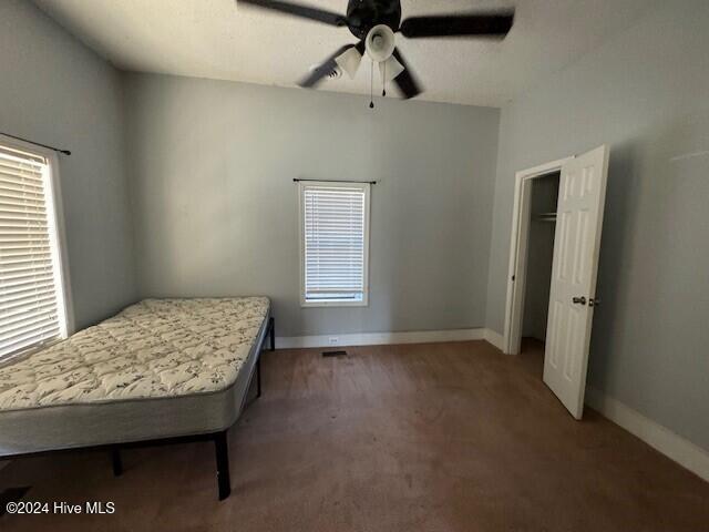 unfurnished bedroom with dark colored carpet and ceiling fan