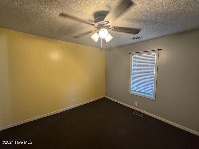 carpeted empty room featuring ceiling fan and a textured ceiling