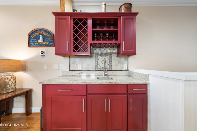 bar with light stone countertops, sink, dark hardwood / wood-style floors, backsplash, and crown molding