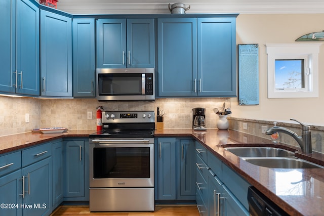 kitchen featuring blue cabinetry, backsplash, sink, and stainless steel appliances