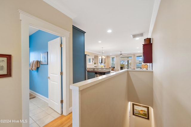 hall featuring crown molding, sink, and light tile patterned floors