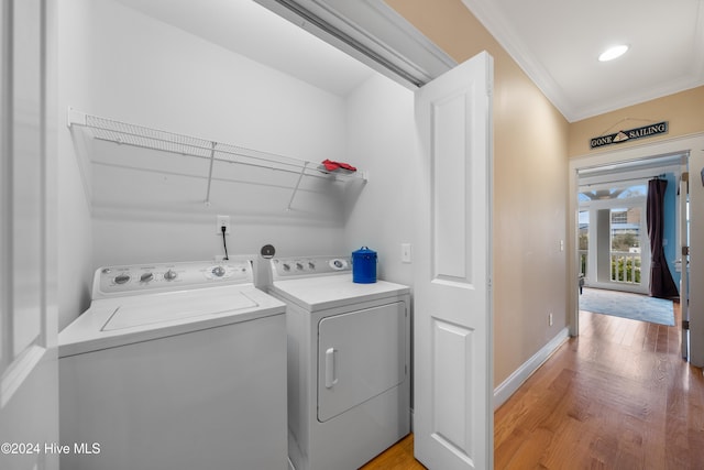 clothes washing area with hardwood / wood-style floors, washing machine and dryer, and crown molding