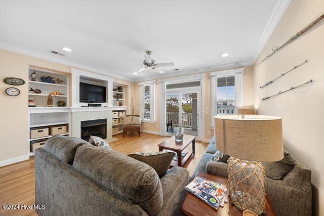 living room with ceiling fan, crown molding, and light hardwood / wood-style flooring