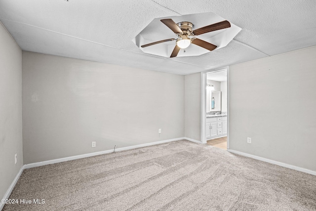 spare room with ceiling fan, light colored carpet, and a textured ceiling