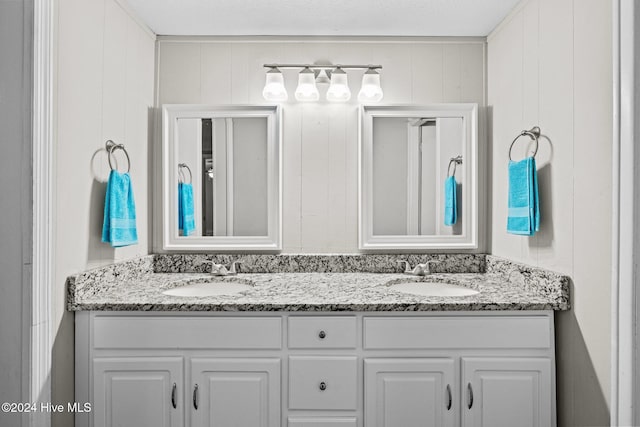 bathroom with wooden walls, vanity, and a textured ceiling