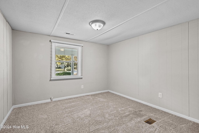 unfurnished room with carpet and a textured ceiling