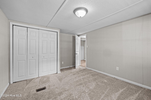 unfurnished bedroom featuring a textured ceiling, light carpet, and a closet