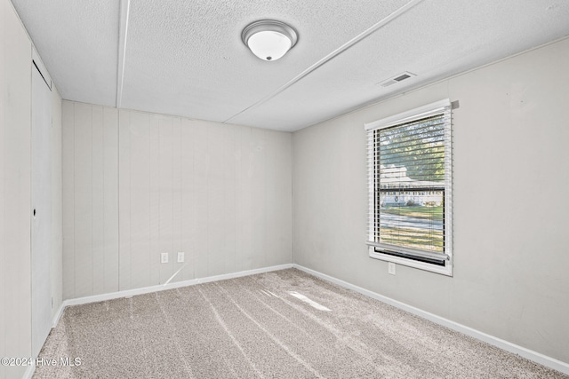 carpeted empty room with a textured ceiling