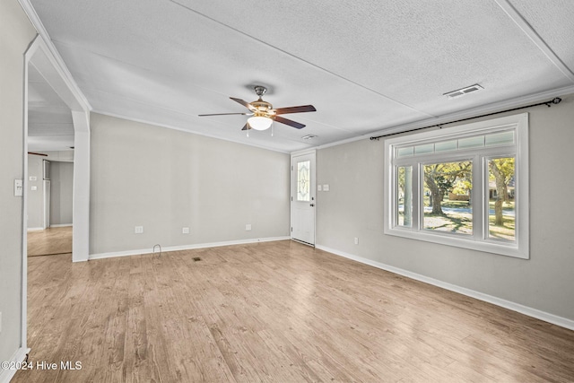 spare room featuring a textured ceiling, light hardwood / wood-style floors, ceiling fan, and crown molding