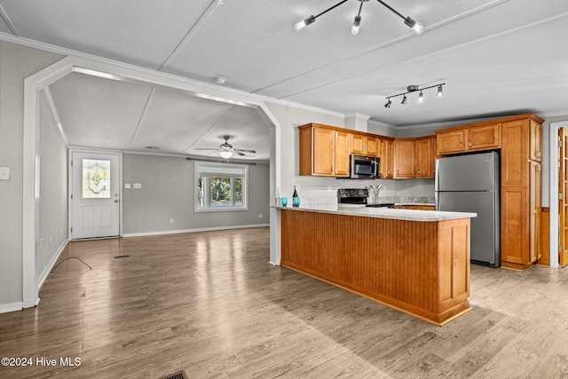 kitchen with stainless steel appliances, kitchen peninsula, crown molding, a textured ceiling, and light wood-type flooring