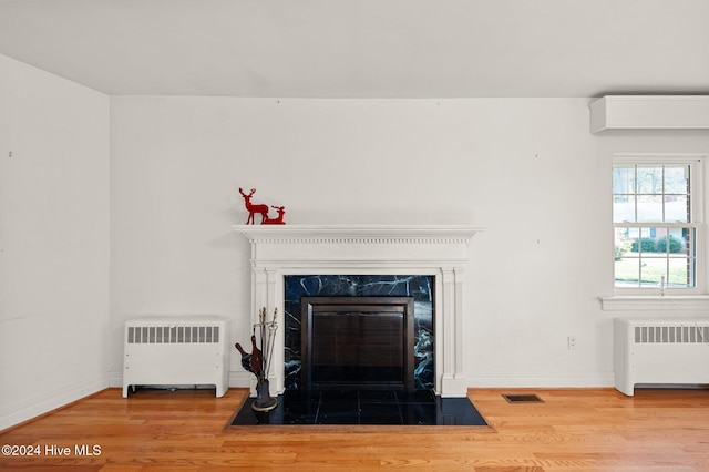 unfurnished dining area featuring radiator heating unit, light wood-type flooring, and a notable chandelier