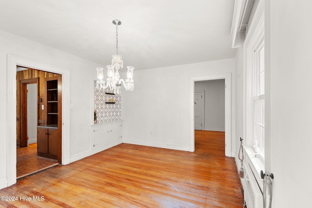 unfurnished dining area with hardwood / wood-style floors and an inviting chandelier