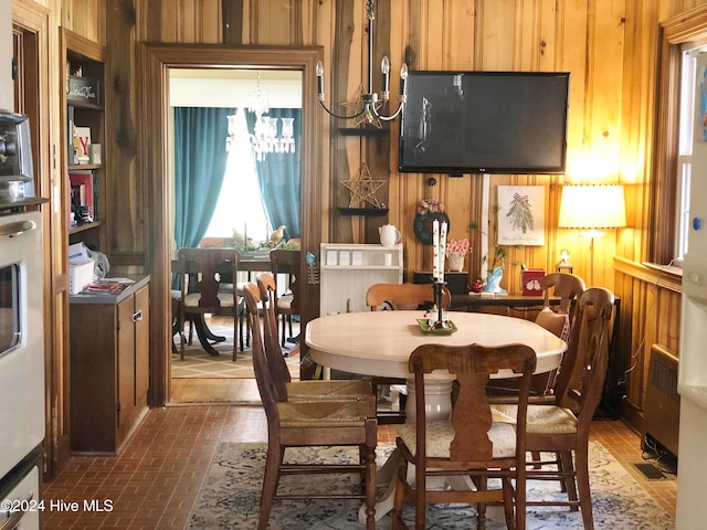 dining room featuring wooden walls and a chandelier