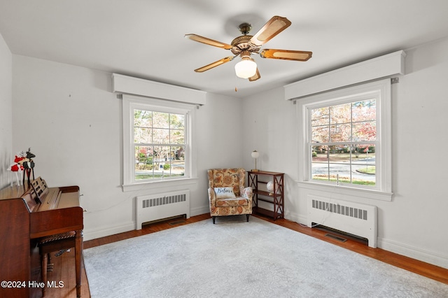 living area featuring radiator heating unit, a healthy amount of sunlight, and hardwood / wood-style flooring