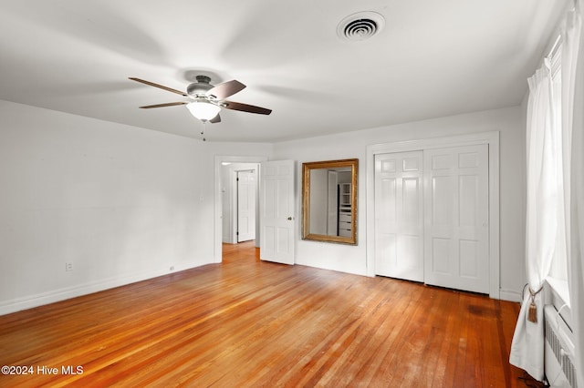 unfurnished bedroom featuring ceiling fan, light hardwood / wood-style floors, and a closet