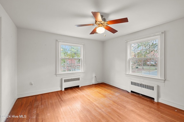 empty room with light hardwood / wood-style floors, radiator, and ceiling fan