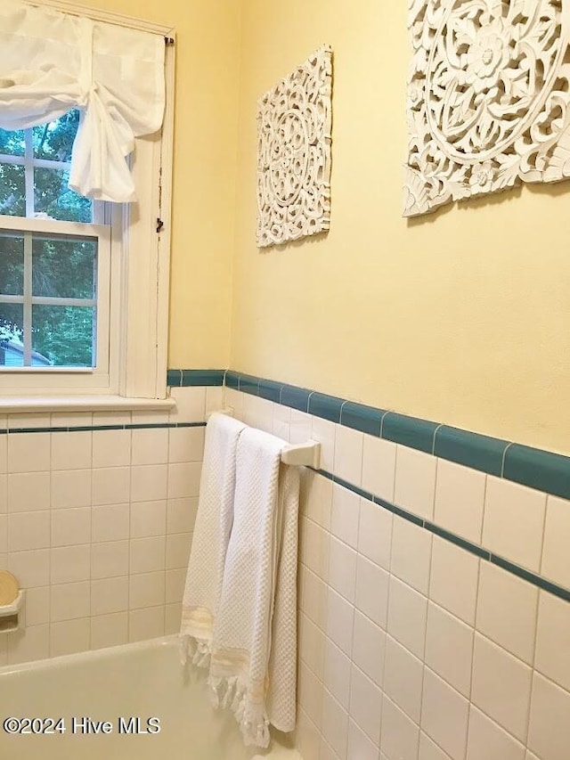 bathroom with a washtub and tile walls