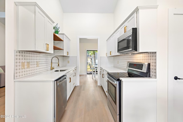 kitchen with tasteful backsplash, stainless steel appliances, sink, light hardwood / wood-style floors, and white cabinetry