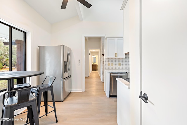 kitchen with appliances with stainless steel finishes, light wood-type flooring, tasteful backsplash, ceiling fan, and white cabinets