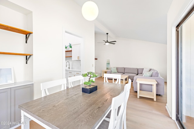 dining room featuring ceiling fan, light hardwood / wood-style floors, sink, and vaulted ceiling