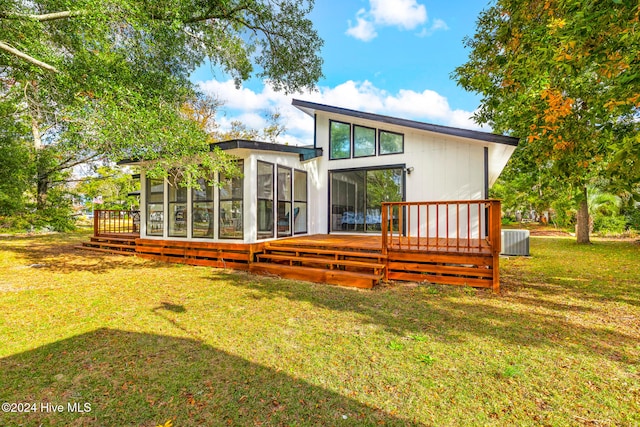 rear view of house featuring a sunroom, central AC unit, a deck, and a lawn