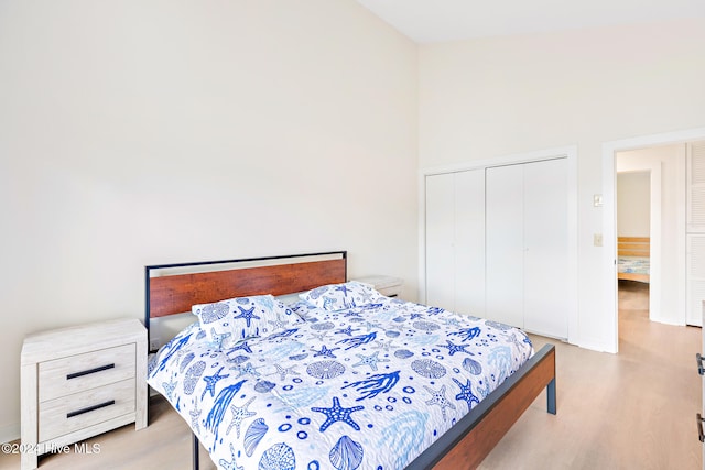 bedroom featuring a towering ceiling, light wood-type flooring, and a closet