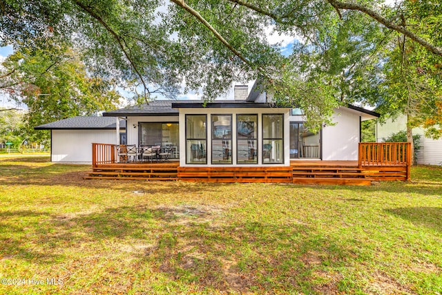 rear view of property featuring a sunroom, a deck, and a lawn