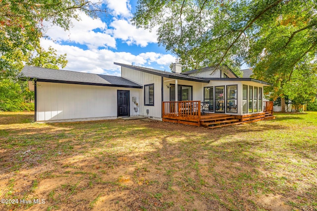 back of property featuring a sunroom, a deck, and a lawn