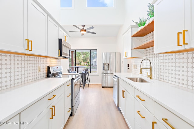 kitchen featuring decorative backsplash, appliances with stainless steel finishes, sink, light hardwood / wood-style flooring, and white cabinetry