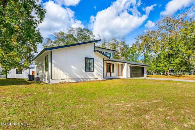 rear view of property with a lawn, central AC, and a garage