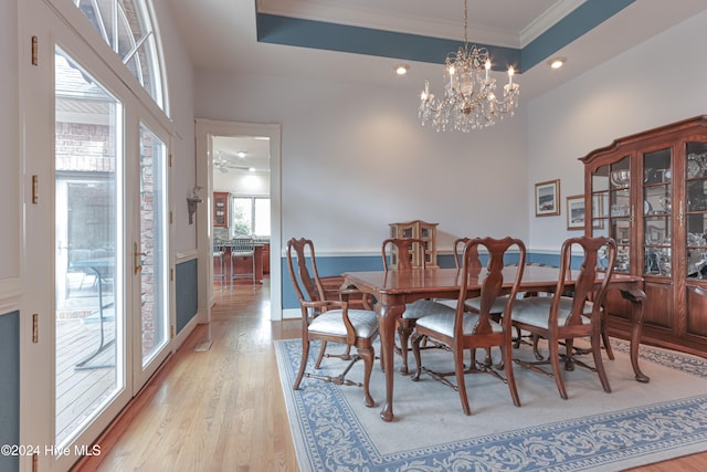 dining room featuring ceiling fan with notable chandelier, light hardwood / wood-style floors, ornamental molding, and a tray ceiling