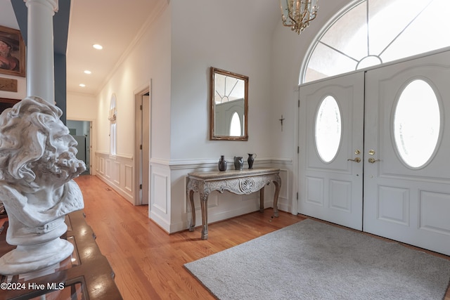 foyer entrance featuring crown molding, a chandelier, and light wood-type flooring